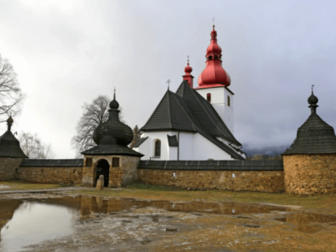 A church with two red and white domes on top of it.